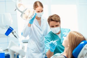 Un dentista y una enfermera están tratando al paciente. Se inclinan sobre él con mascarillas médicas. Tienen instrumentos médicos en las manos.