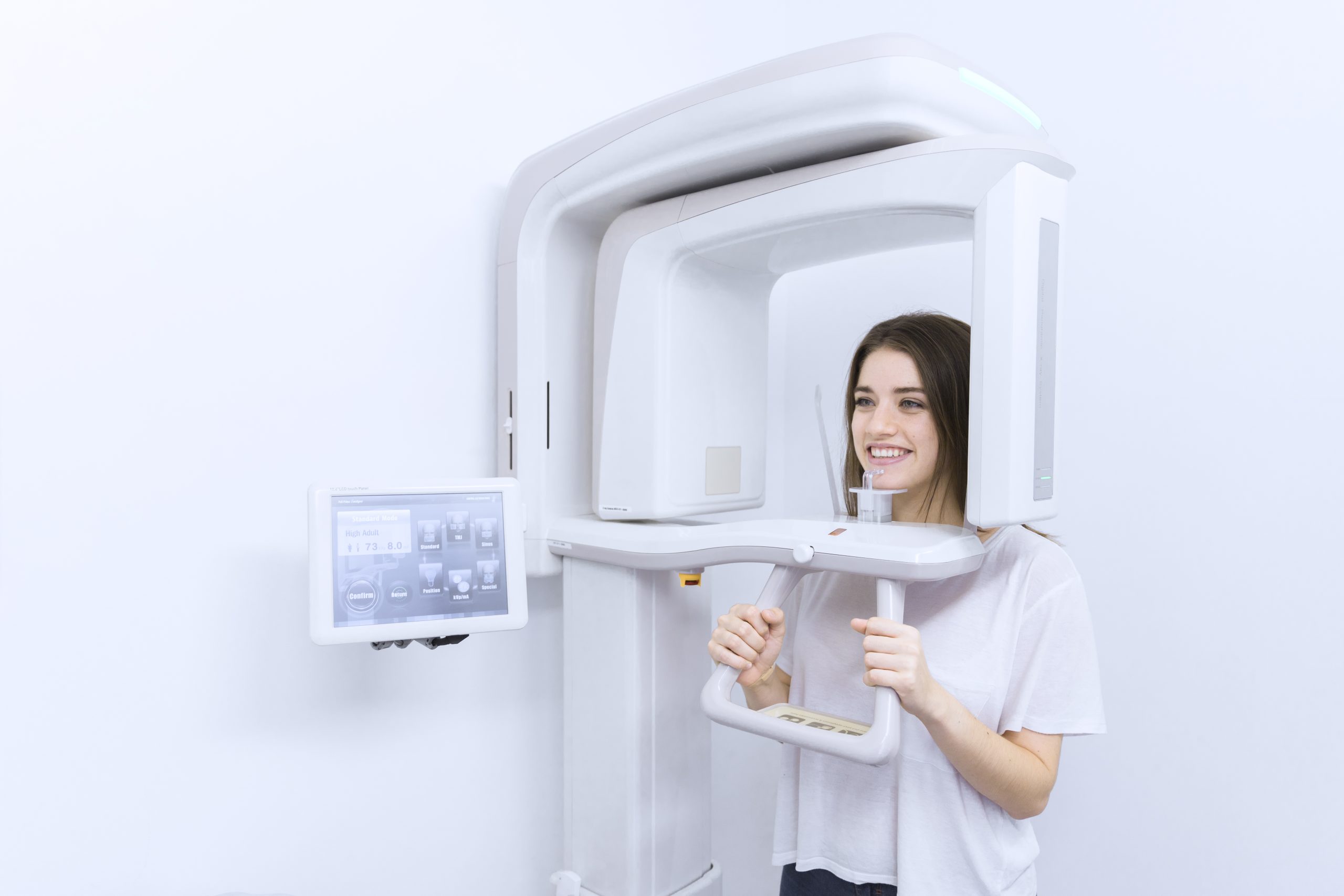 feliz-joven-paciente-dental-femenina-pie-maquina-digital-rayos-x-cefalometrico